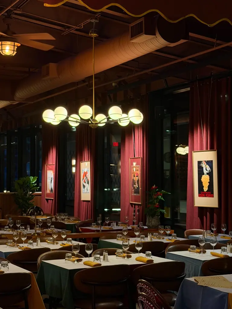 Entrecôte dining room with burgundy curtains, globe chandelier, and set tables