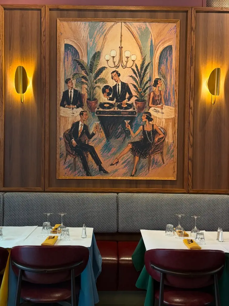 Entrecôte booth seating beneath a large Parisian mural and brass sconces