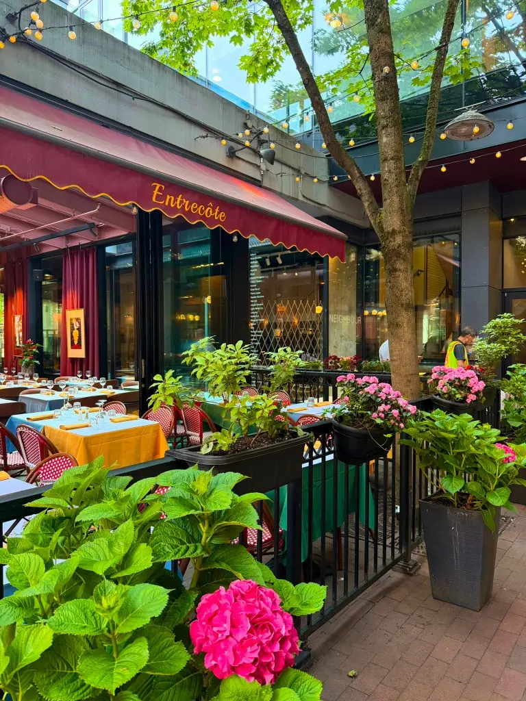 Entrecôte patio with burgundy awning, flowers, and Parisian cafe tables